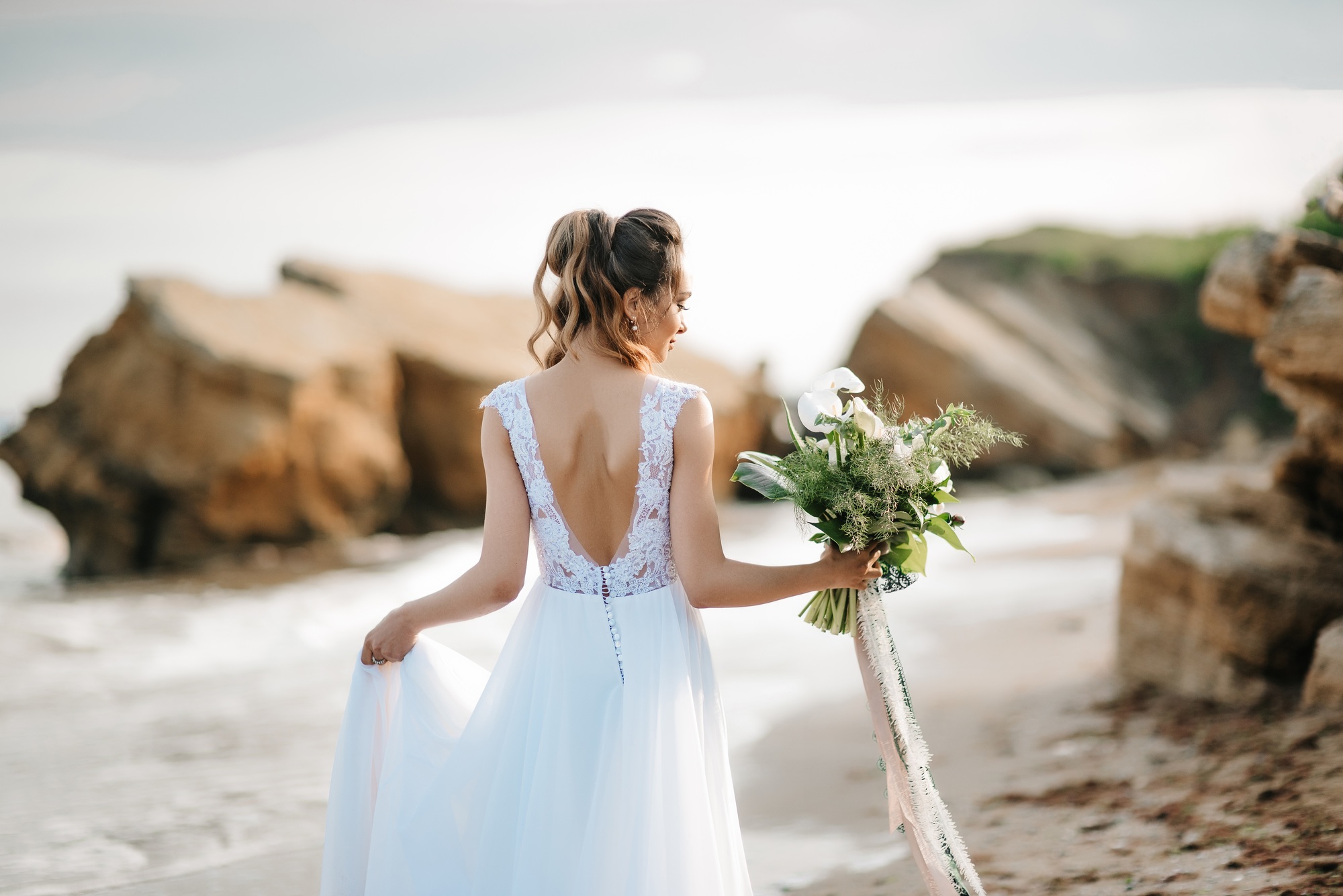 bride with a wedding bouquet on the shore sea