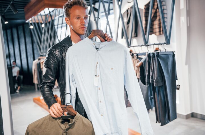 Big choice. Young guy in modern store with new clothes. Elegant expensive wear for men