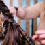 Hairstylist curling a client hair while doing her wedding hairstyle at the hairdressing salon.